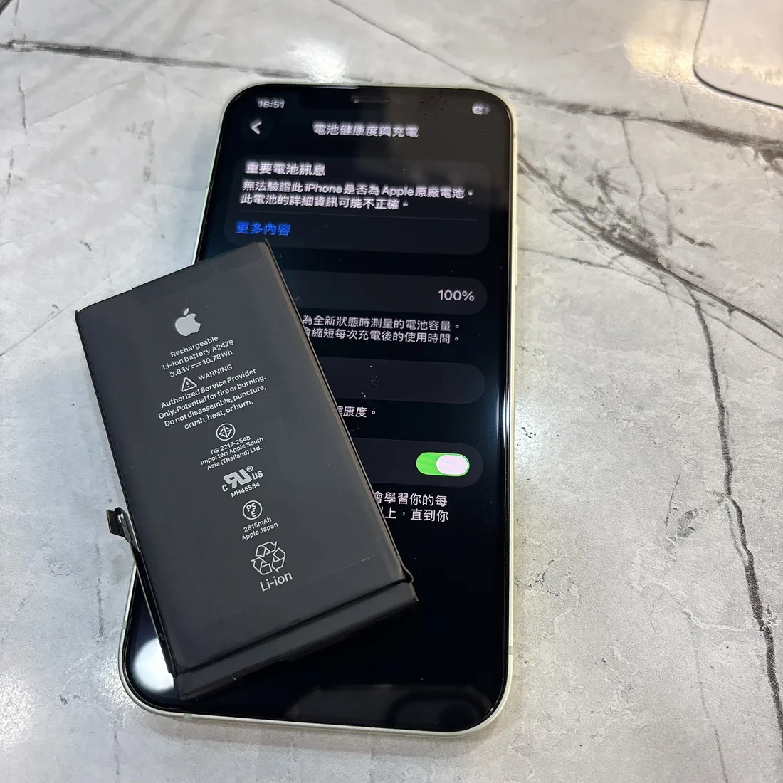 白夫人3C 東區崇善店 iPhone 12 換電池後,電池健康度顯示 100%,前方是換上的電池