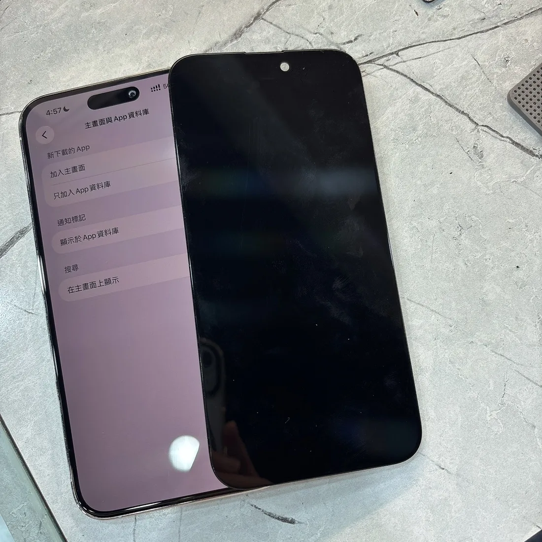 iPhone 14 Pro Max 清潔搶救並換上新螢幕後正常顯示,上面疊著換下來的水損舊螢幕