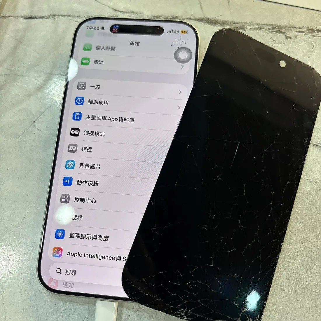iPhone 17 Pro 換上新螢幕後正常顯示,右邊是拆下來的蜘蛛網狀碎裂舊螢幕