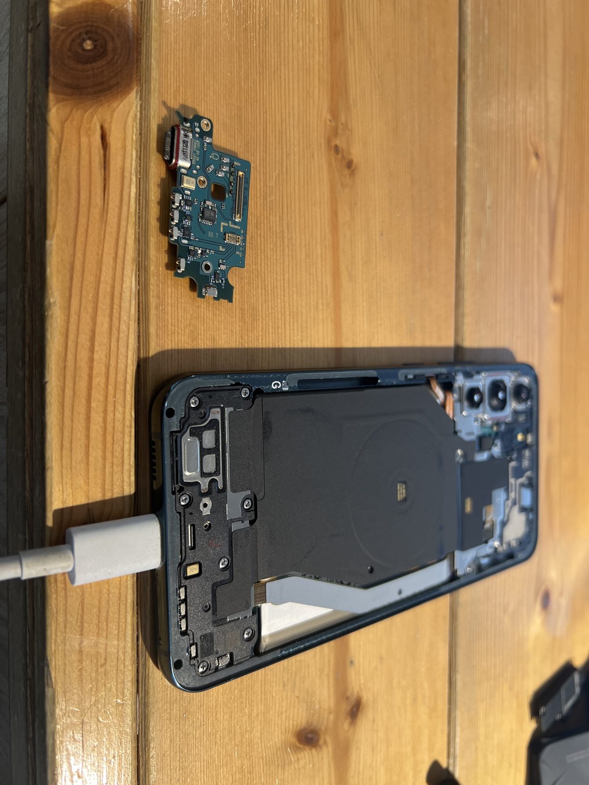 Galaxy S22 Ultra 拆下的充電埠小板與拆解中的機身