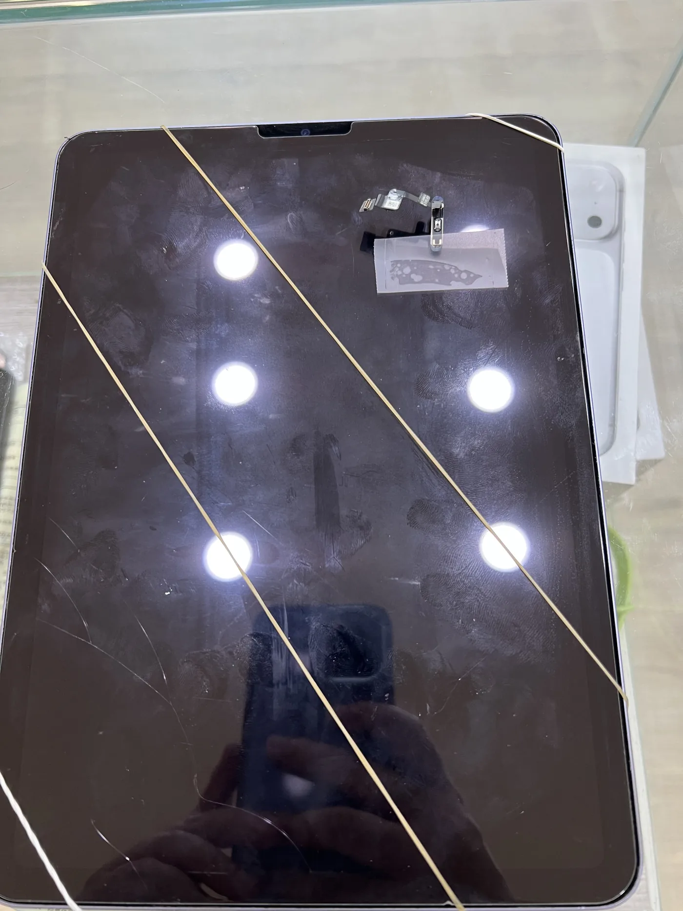 iPad Air 換完電源鍵排線後用橡皮筋綑綁固定,螢幕上放著換下的舊按鍵排線