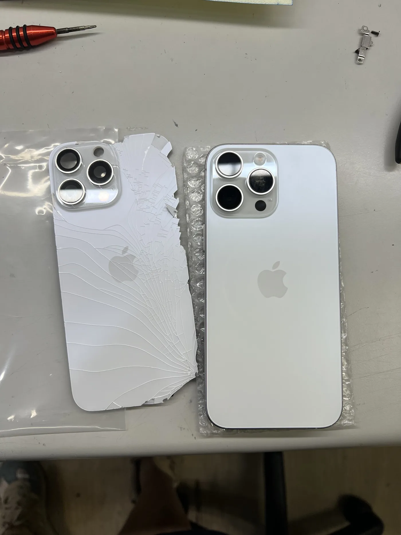 iPhone 16 Pro Max 整片拆下的破裂舊背蓋(左)與準備換上的新背蓋(右)