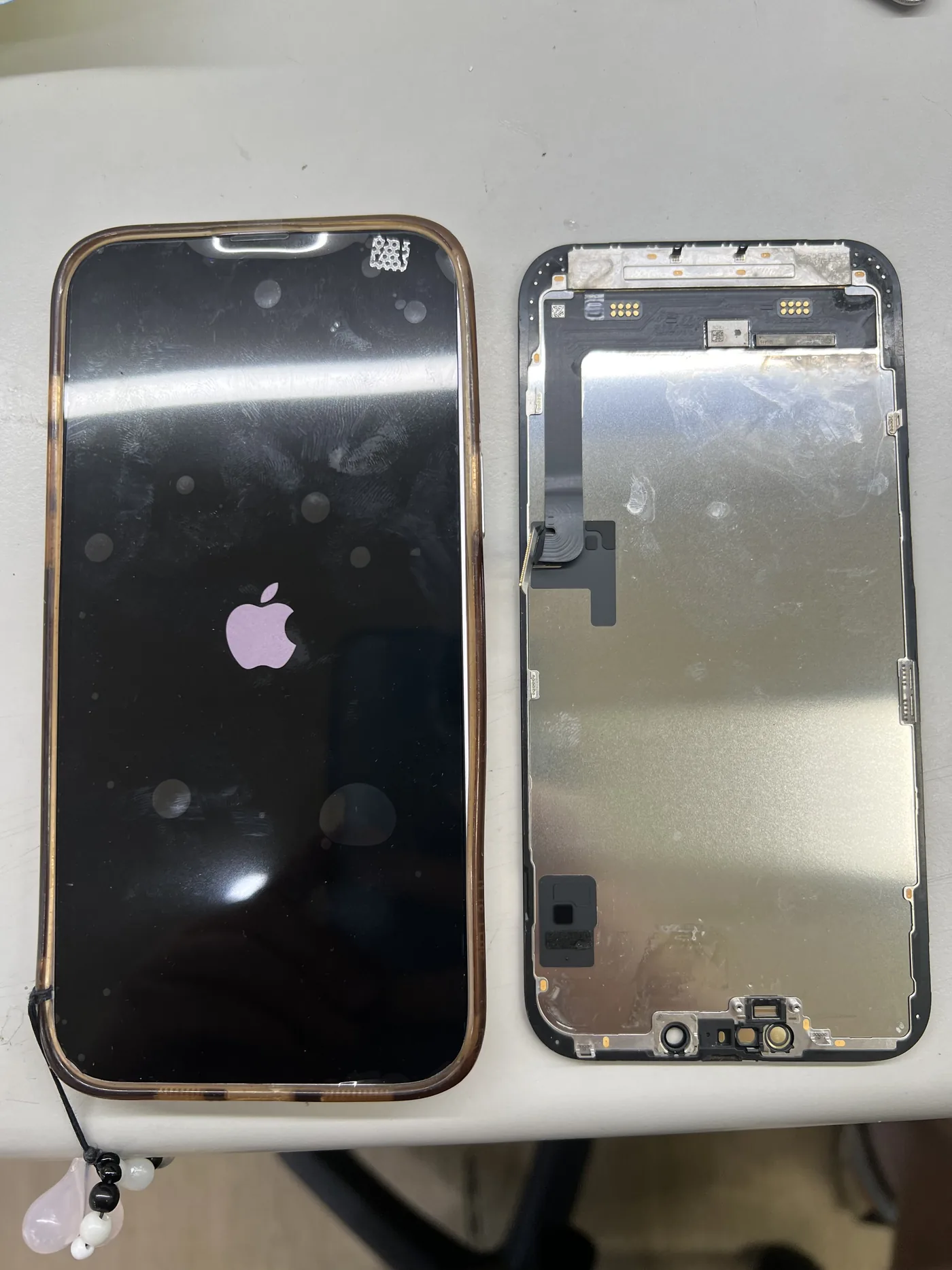 iPhone 左邊換上新螢幕後開機顯示 Apple 標誌,右邊是拆下的舊螢幕總成背面