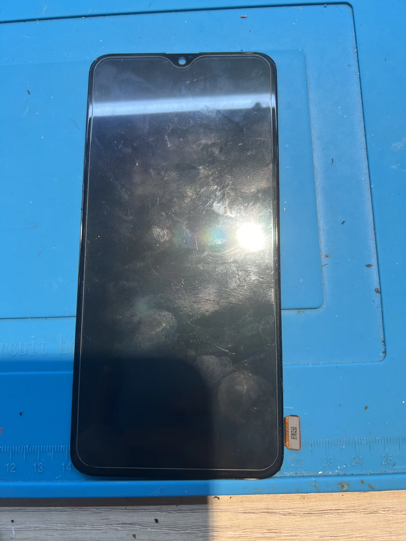 OPPO Reno5 更換用的螢幕總成放在藍色維修墊上